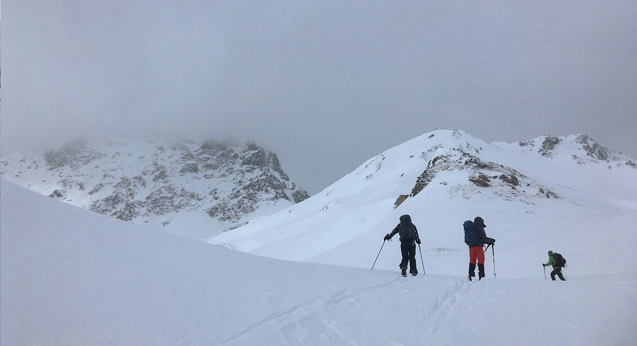 A crew fighting the wind on a ski tour.